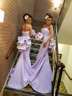 two girls in purple dresses standing on stairs