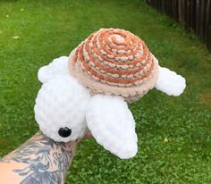 a hand holding a small stuffed animal with a hat on top of it's head