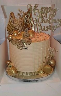 a white cake with gold decorations in a box