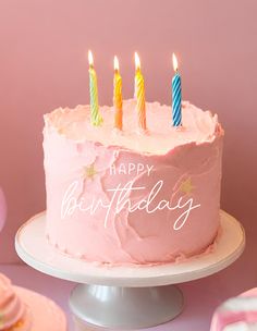 a birthday cake with pink frosting and lit candles