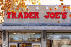 a trader joe's store front with autumn leaves on the tree and cars parked outside