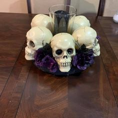 there is a vase with skulls and flowers in it on top of a wooden table