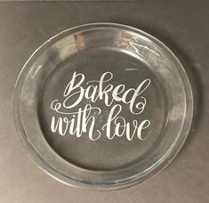 a glass plate with the words baked with love written in white ink on it, sitting on a table