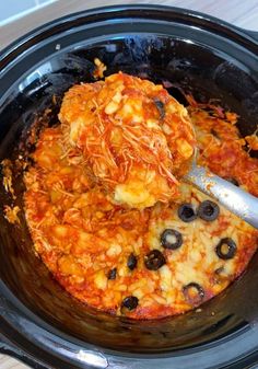 a close up of a pizza in a crock pot with olives and cheese