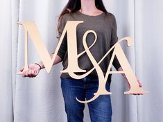 a woman holding two wooden letters that spell m and a