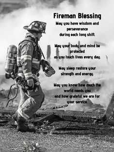 a black and white photo of a fireman walking in front of a burning building