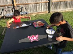 two young boys sitting at a table making crafts