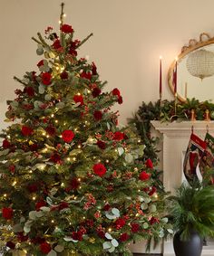 a decorated christmas tree in a living room with red and green decorations on the mantle