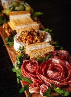 an assortment of meats and cheeses are arranged on a long wooden platter