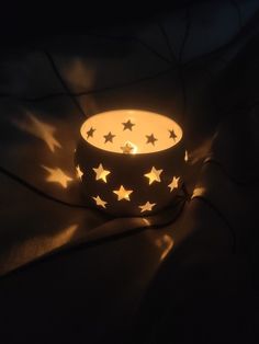 a lit candle with stars on it in the dark