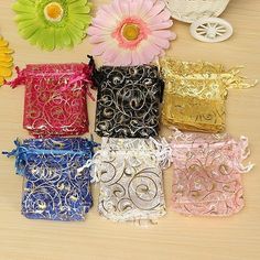 several different colored bags sitting on top of a wooden table next to flowers and scissors