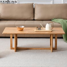 a wooden table sitting in front of a couch with a tea pot and cup on it