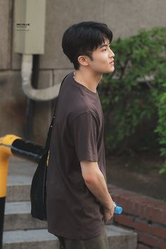 a young man walking down the street with a backpack on his back and a water bottle in his hand