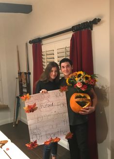 a man and woman holding up a sign in front of a window with sunflowers