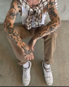 a man with tattoos sitting on the ground