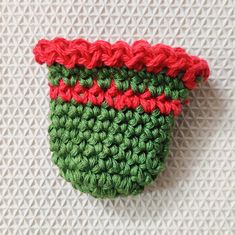 a crocheted green and red cup on a white surface