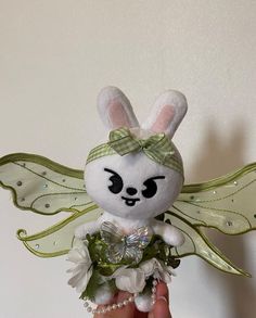 a hand holding a small stuffed animal with flowers in it's belly and wings