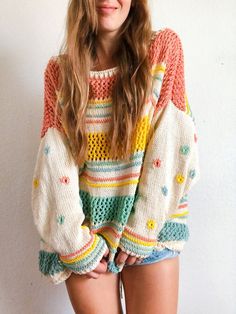 a young woman is posing for the camera with her hands on her hips and wearing a multicolored sweater