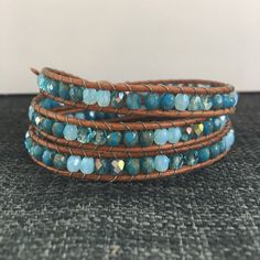 three wrap bracelets with blue beads and brown leather cords on a carpeted surface