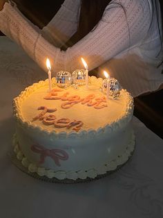 a woman sitting in front of a cake with lit candles