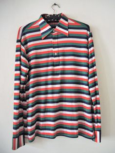 Vintage longsleeve polo shirt from the 1990s. Beautiful stripe pattern in vibrant colour mix. Big collar. Halfway buttoned front. Decorative tuck on the back. Buttoned cuffs. Style with your favorite jeans and sunglasses for a preppy look! BRAND: einhorn ERA: 1990s COLOR: Blue, white, red, green stripes MATERIAL: 65% polyester, 35% cotton SIZE: M (please check measurements) MEASUREMENTS: Pit to pit 52cm, length without collar 65cm, sleeve length from shoulder 60cm CONDITION: Very good vintage co Cotton Polo Sweater With Striped Collar, Casual Long Sleeve Polo Shirt With Striped Collar, Retro Polo Collar Tops For Fall, Classic Long Sleeve Polo Shirt With Contrast Stripes, Striped Long Sleeve Polo Shirt, Casual Striped Long Sleeve Polo Shirt, Casual Long Sleeve Striped Polo Shirt, Collared Tops With Vertical Stripes For Fall, Retro Long Sleeve Cotton Polo Sweater