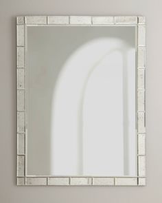 a white square mirror sitting on top of a wall