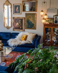 a living room filled with blue couches and pictures on the wall next to potted plants