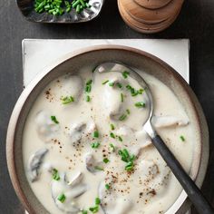 a bowl of soup with meatballs and green onions on the side next to a spoon