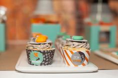 two cupcakes sitting on top of a white plate with orange and green decorations