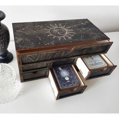 an open wooden box sitting on top of a table next to a vase and candle