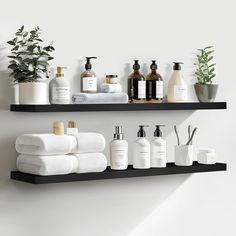 two black shelves with white towels, soaps and lotion bottles on them next to a potted plant