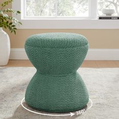 the foot stool is made out of knitted material and sits on a rug in front of a window