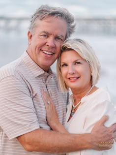 an older couple embracing each other on the beach