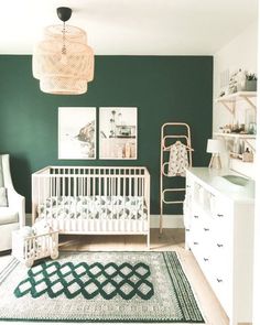 a baby's room with green walls, white furniture and pictures on the wall