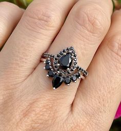 a woman's hand with a black diamond and silver ring on top of it