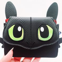 a black wallet with green eyes and ears