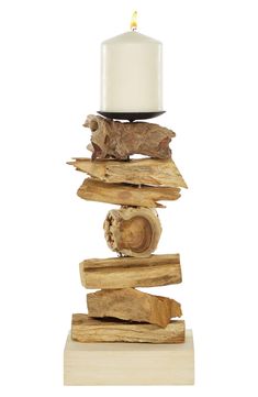 a candle that is sitting on top of some driftwood and wood pieces in front of a white background