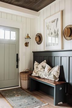 a black bench sitting in front of a door next to a rug and two pictures on the wall