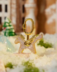 a gold brooch sitting on top of snow covered ground next to a christmas tree