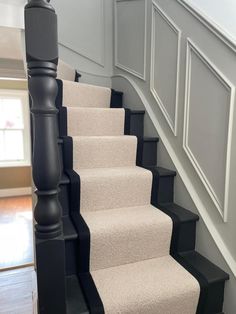 there is a set of stairs with carpet on the bottom, and black handrails