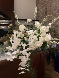 white flowers and greenery are arranged in a vase on the counter top at a restaurant