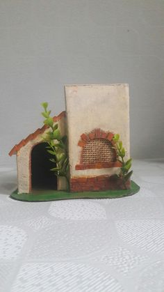 a small dog house made out of clay with plants growing in the front and side