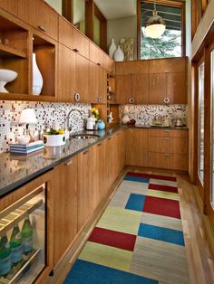 a kitchen with wooden cabinets and colorful rugs on the floor next to an open refrigerator