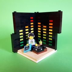 a lego man with headphones on in front of a record player and sound board