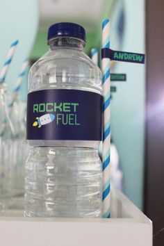 a bottle of rocket fuel sitting on top of a white counter next to two blue and white striped straws