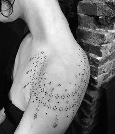 the back of a woman's shoulder with small dots on her left arm and chest