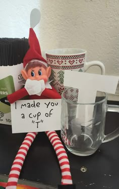 an elf is holding a sign that says i made you a cup of tea with it