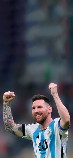 a male soccer player is raising his fist up in the air and smiling at the camera