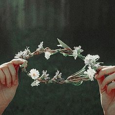 two hands are holding flowers in front of the headpiece, while another hand holds it with both hands