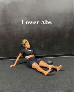 a woman laying on the ground in front of a black wall with lower abss